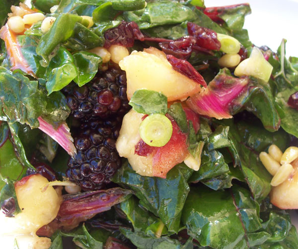 Kale and rainbow chard salad with peaches, blackberries & pinenuts